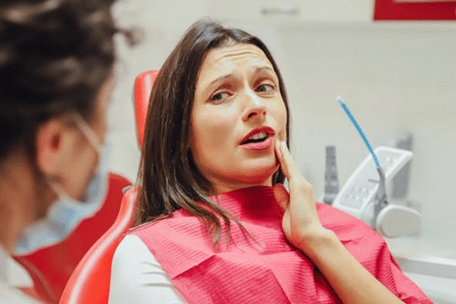 Woman in pink dental bib receiving dental examination in modern dental office.