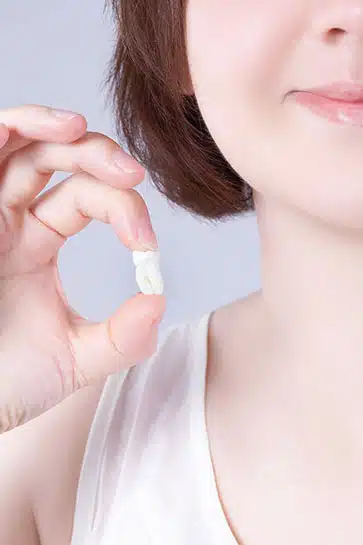 Woman holding dental floss near her mouth against a light blue background.