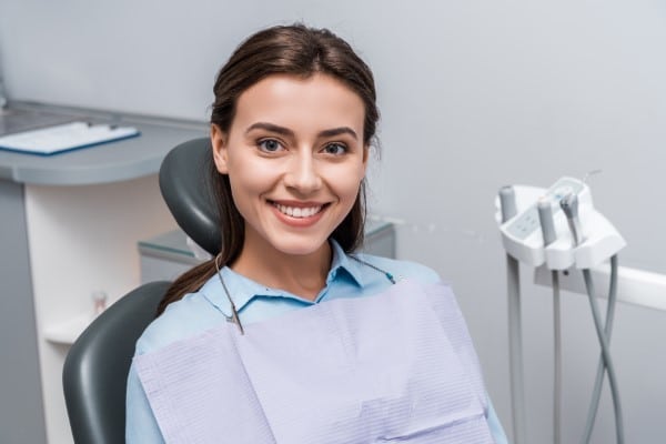 Smiling female dental professional in light blue scrubs seated in dental chair at Danville Family Dental office.