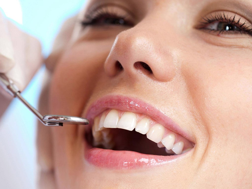 Woman receiving dental examination with mirror tool at dentist office