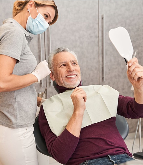 Dentist showing male patient dental x-rays in clinical examination room setting.